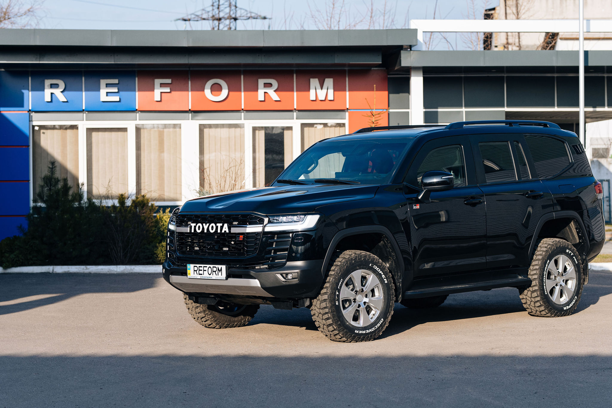 Armored Toyota Land Cruiser 300 GR near the REFORM production facility — front and side view